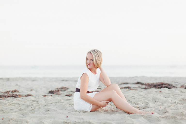 woman sitting on Santa Barbara beach in white dress with blonde hair