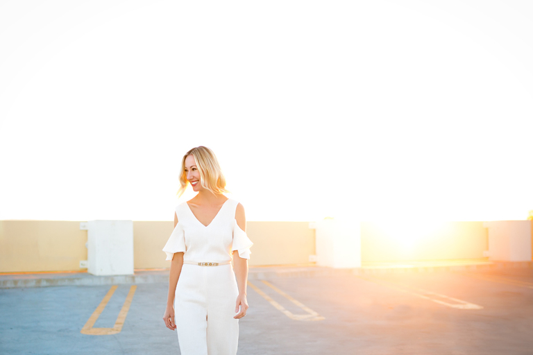 jeneffer jones in club monaco white jumpsuit photographed by Sarah Tyler at the Livermore parking garage with beautiful sunset behind her