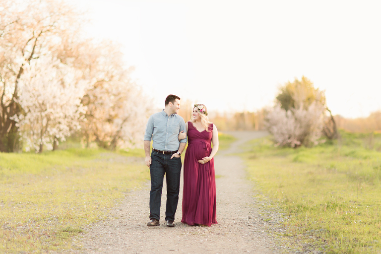 mom pregnant with son walks with husband in a maroon dress