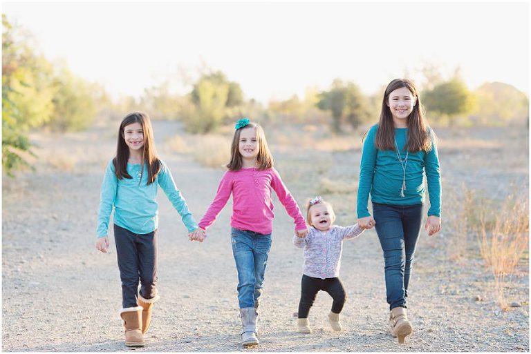 four little girls holding hands walking together