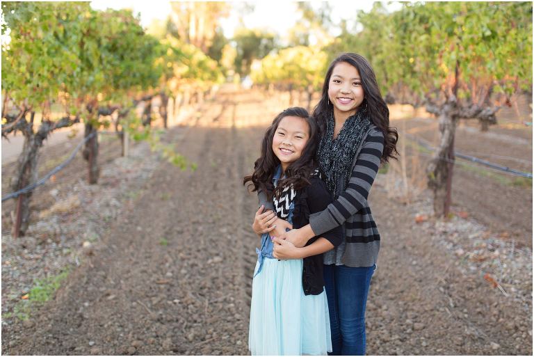 Sisters hugging in rows of grapevines in Livermore