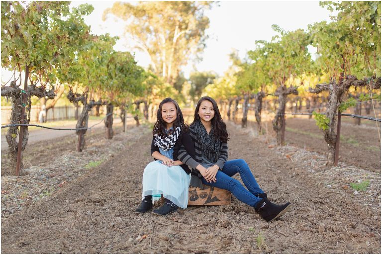 Kids sitting on box between rows of grapevines in Livermore