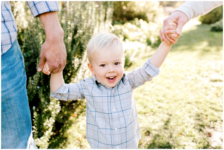 little boy holding mom and dads hands smiling