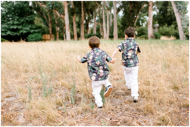 boys running in field holding hands